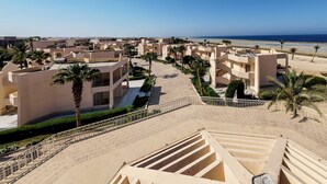Un complexe hôtelier comprenant plusieurs bâtiments, des palmiers et offrant une vue sur la plage.