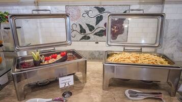 Ein Buffet mit zwei Metallempfangstischen, einer mit der Aufschrift 'CAVOLI MIX' und der andere 'CABBAGE MIX', und einem Löffel auf dem Boden.