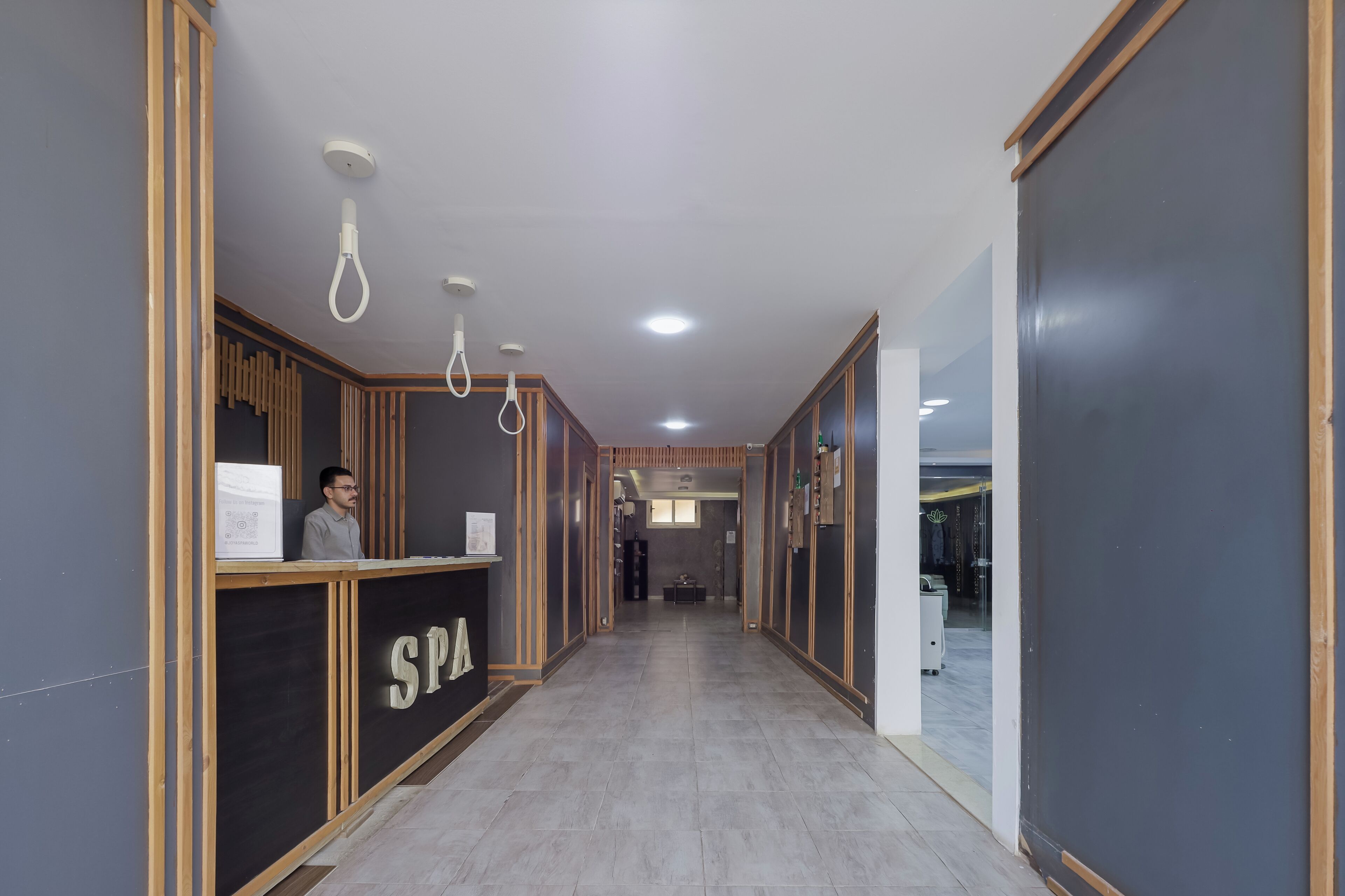 A hallway with a reception desk labeled 'SPA', wooden paneling, and a tiled floor.