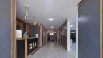 A hallway with a reception desk labeled 'SPA', wooden paneling, and a tiled floor.