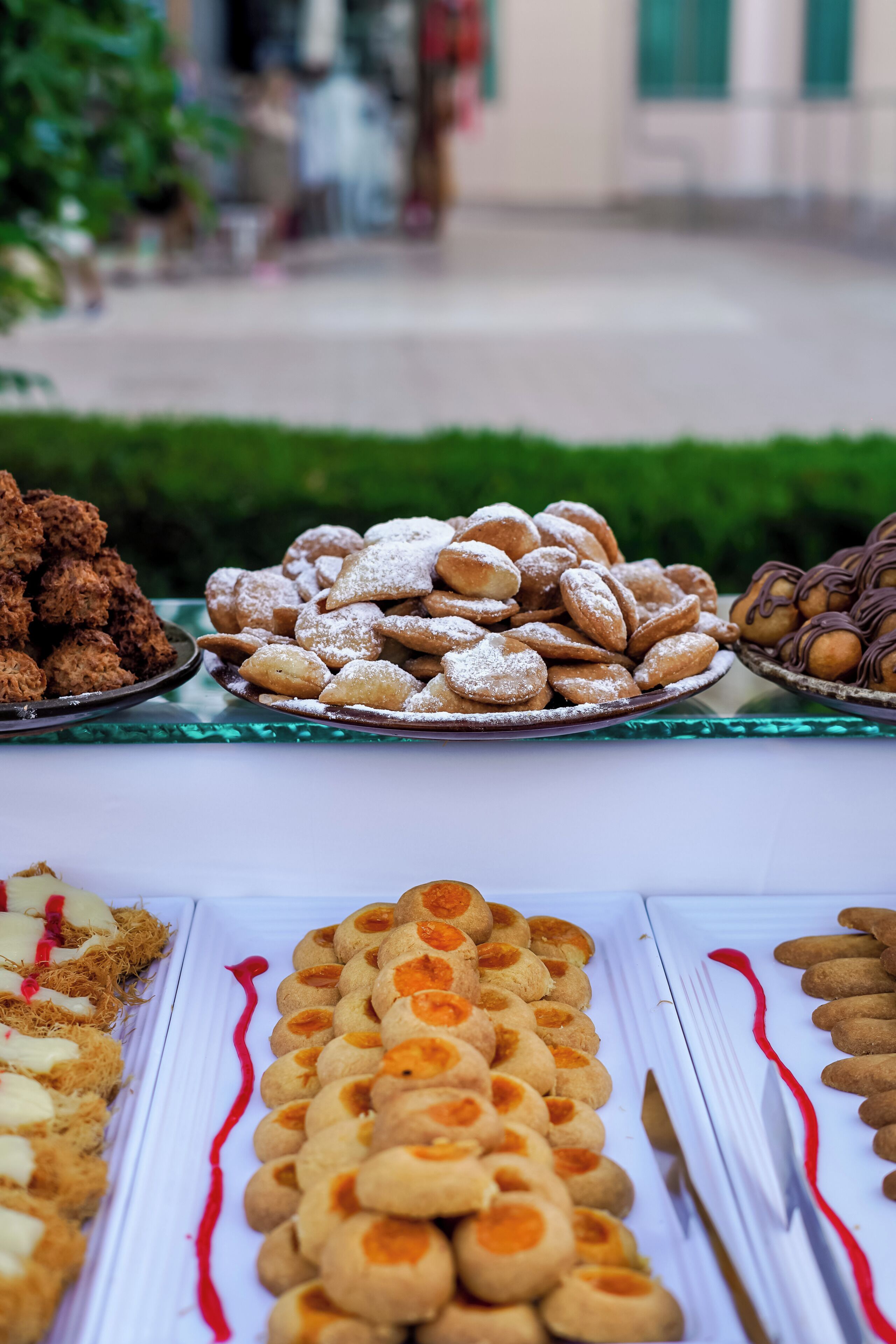 A variety of pastries displayed on a table with a city street in the background.