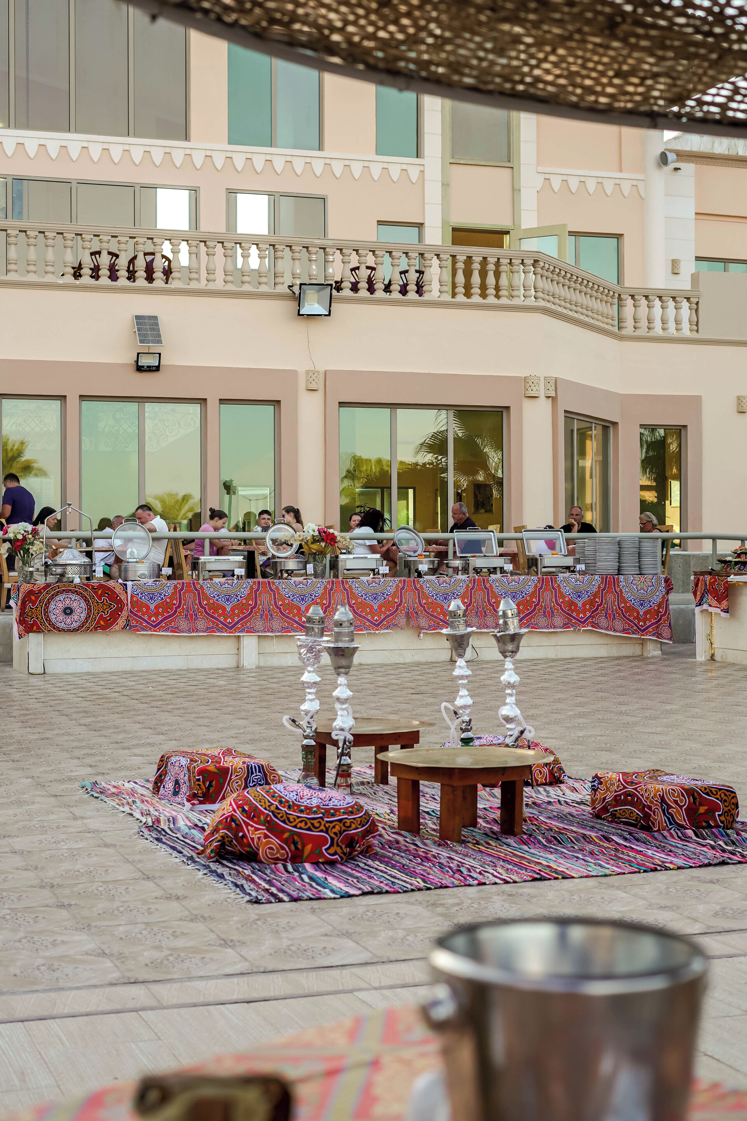 A courtyard with outdoor seating, a decorative fountain, and a building with large windows in the background.