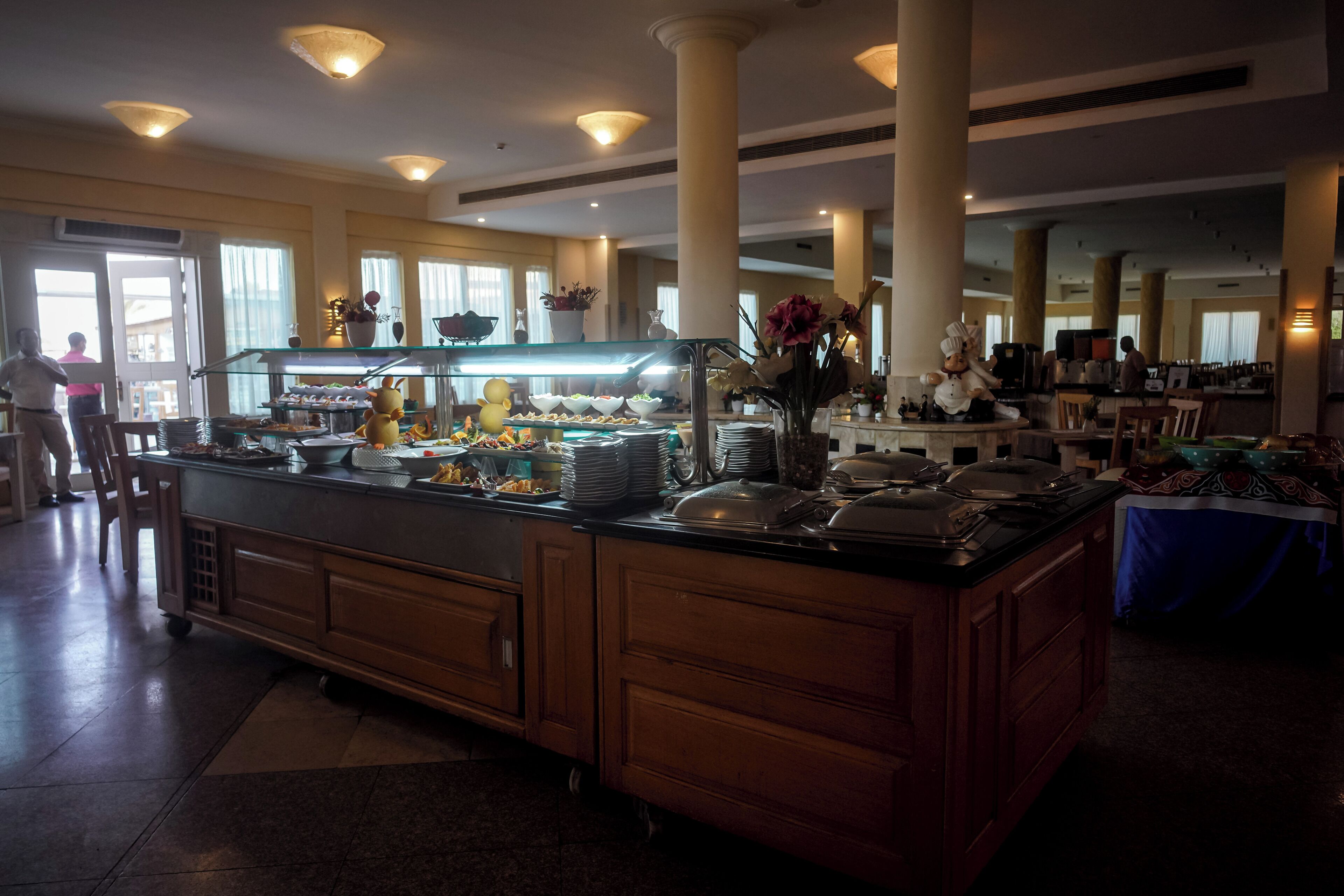 Een buffetruimte met diverse gerechten, een centraal bedieningspunt en een zithoek met tafels en stoelen.