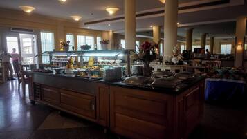 Een buffetruimte met diverse gerechten, een centraal bedieningspunt en een zithoek met tafels en stoelen.