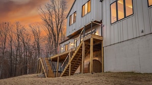 A modern two-story house with a wooden deck and a staircase leading to a balcony. - Luxury Home on trail W Sauna/Hot tub/Steam room (Bella Vista)