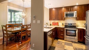 A modern kitchen with wooden cabinets, stainless steel appliances, and a checkered tile floor. - Crystal Ridge by Whistler Retreats (Whistler)