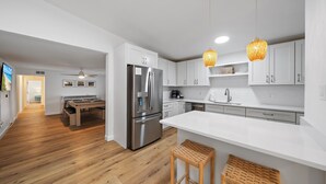 A modern kitchen with white cabinets, a stainless steel refrigerator, and a wooden dining table.
