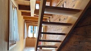 Un interior de madera con techo inclinado, vigas de madera y un banco.