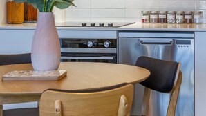 Ett modernt kök med träskåp, en diskmaskin i rostfritt stål, en gasspis och en vas med blommor på bordet.