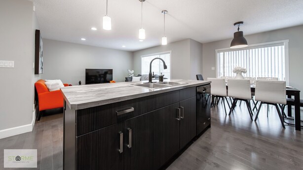 A modern kitchen with a central island, dark cabinetry, and pendant lighting. - Luxury Executive 4BD 2.5B AC home in the exclusive neighbourhood of Windermere (Edmonton)