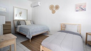 Een slaapkamer met twee bedden, een bureau en een luchtverkoeler aan de muur.