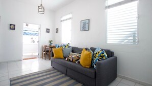 Een moderne woonkamer met een grijze bank, een gestreept tapijt en uitzicht op buiten.