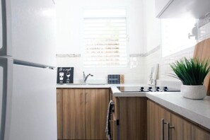 Eine moderne Küche mit Holzschränken, einer weißen Arbeitsplatte, einem Spülbecken und einem Blumentopf.