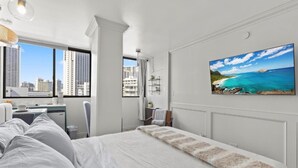 Une chambre d’hôtel moderne dotée d’un grand lit, d’un bureau et offrant une vue sur le paysage urbain grâce à de grandes fenêtres.