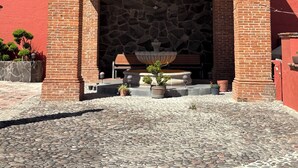 A hotel entrance with a stone facade, a sign reading "Villas San Francisco Hotel," and a stone bench with potted plants. - Villas San Francisco (Huichapan)