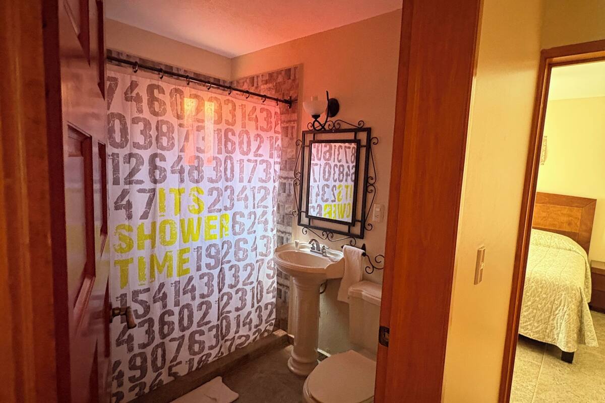 Egy fürdőszoba, amelyben zuhanyfüggönyön számok vannak, emellett mosdókagyló és WC is található benne.