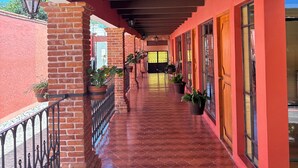 A covered corridor with a tiled floor, brick pillars, and potted plants. - Villas San Francisco (Huichapan)
