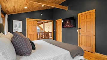 Un dormitorio con una cama, un televisor y una puerta de madera.