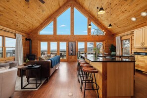 A spacious kitchen with a large island, wooden cabinetry, and a view through the windows.