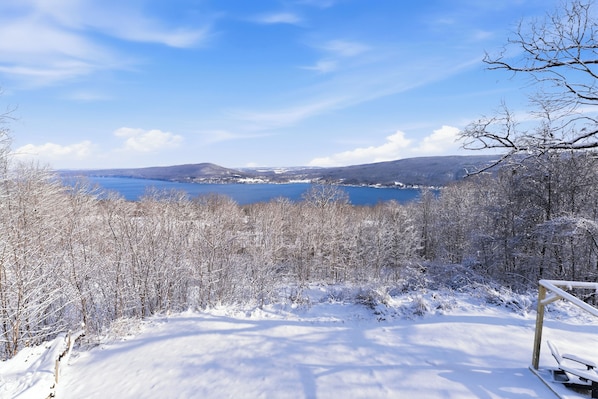 Un paysage enneigé avec un lac et des collines boisées en arrière-plan.