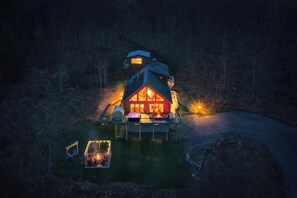 A cabin with a porch, a fire pit, and a deck.