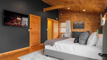 A bedroom with a bed, a fireplace, and a painting on the wall.
