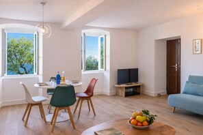 A modern living room with a dining area, a television, and a sofa. - Casa Carmi appartement vue mer à Erbalunga (Brando)