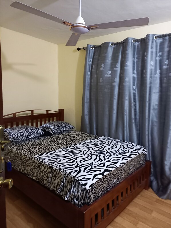 Un dormitorio con cama, ventilador de techo y cortinas.