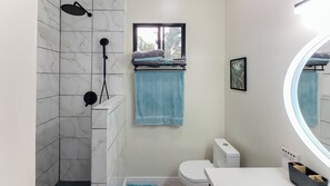 Ein Badezimmer mit Dusche, Toilette, Waschbecken und einem Fenster mit Blick.