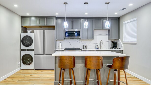 A modern kitchen with stainless steel appliances, wooden bar stools, and pendant lighting. - Luxury, well stocked Murray apartment. (Murray)