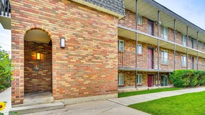A multi-story brick building with a central entrance, balconies, and a small lawn area. - Luxury, well stocked Murray apartment. (Murray)