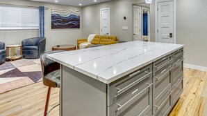 A modern kitchen with a large island, stainless steel appliances, and pendant lighting. - Luxury, well stocked Murray apartment. (Murray)