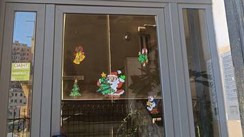 Ein Gebäudeeingang mit einem Metallschild über der Tür, einem Fenster mit Weihnachtsdekoration und einem Schlüsselloch in der Tür.
