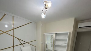A bedroom with two beds, a wardrobe, and a ceiling light fixture. - Golden Hour Apartment (Bursa)