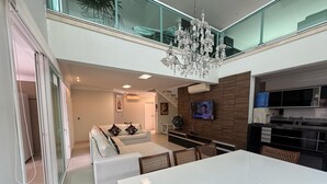 Ein modernes Wohnzimmer mit einem weißen Sofa, einem Esstisch und einer Chandelüster.