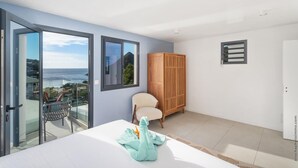 Une chambre moderne avec balcon, une armoire en bois et vue sur la mer.
