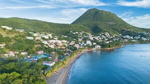 Une ville côtière avec une plage, des maisons et une montagne en arrière-plan.