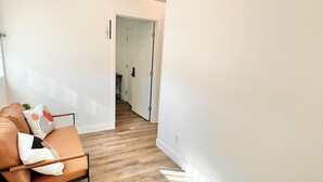 Un interno moderno con pavimento in legno, un divano in pelle con cuscini e una parete bianca.