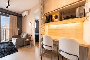A compact living space with a kitchenette, a sofa, a small table, and a chair. - Estúdio Premium Vila Olímpia -ap1901 (Sao Paulo)