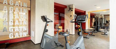 Un gimnasio con bicicletas estáticas, una pared con mensajes motivacionales y diverso equipo de ejercicio.