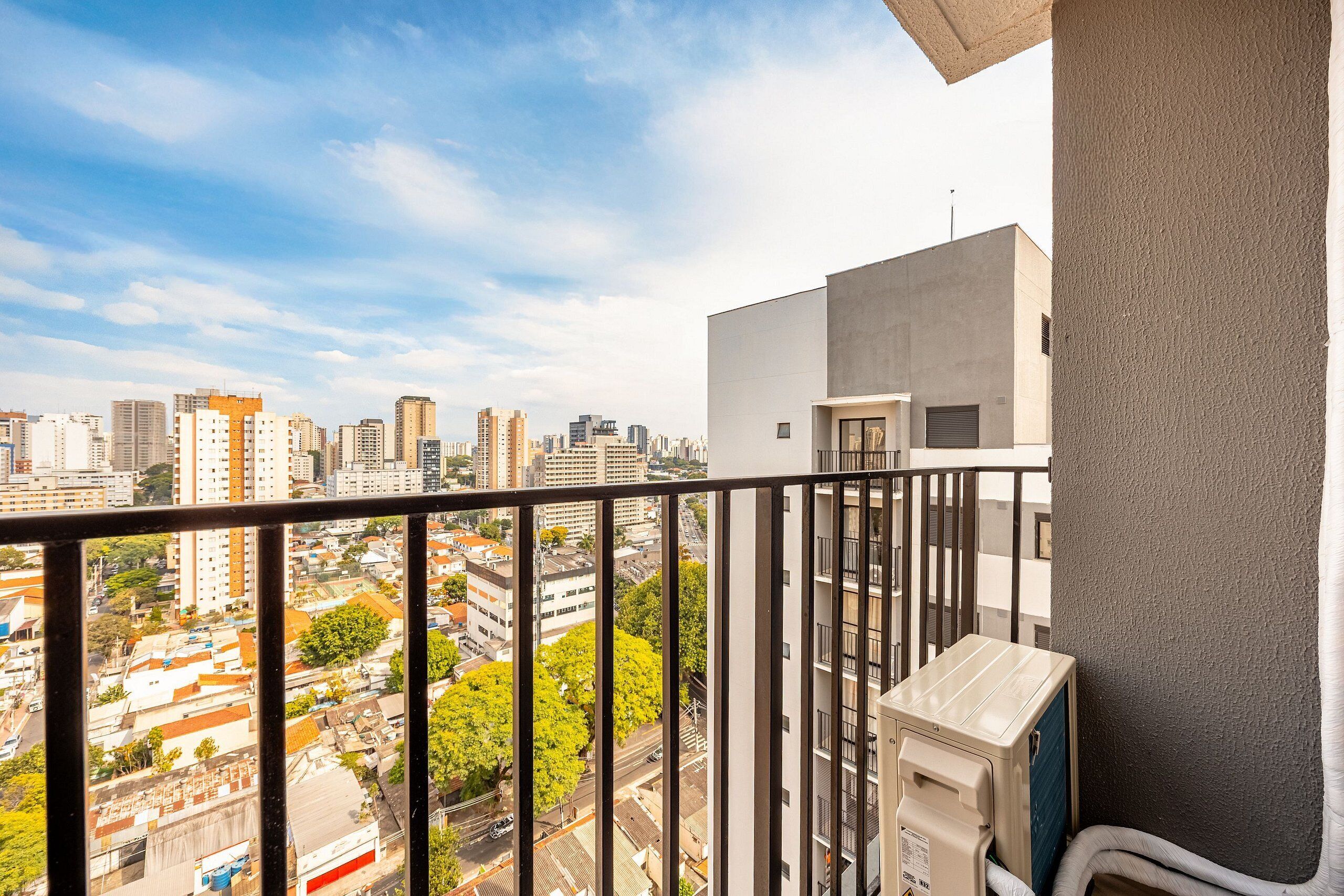 A balcony with a city view, a water heater, and a textured wall.
