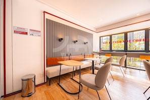 A modern interior with seating, tables, and a view through large windows. - Estúdio Premium Vila Olímpia -ap1901 (Sao Paulo)