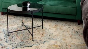 Ein grünes Sofa, ein runder Couchtisch und zwei abstrakte Bilder an der Wand.