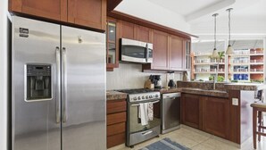 Una cocina moderna con electrodomésticos de acero inoxidable, armarios de madera, microondas integrado y vistas al balcón exterior.