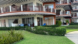 Un hotel con un balcón curvo, varios pisos y un césped bien cuidado.