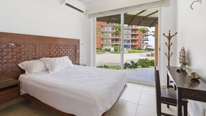 Una habitación de hotel con una cama, un escritorio y vistas a un edificio con balcones.