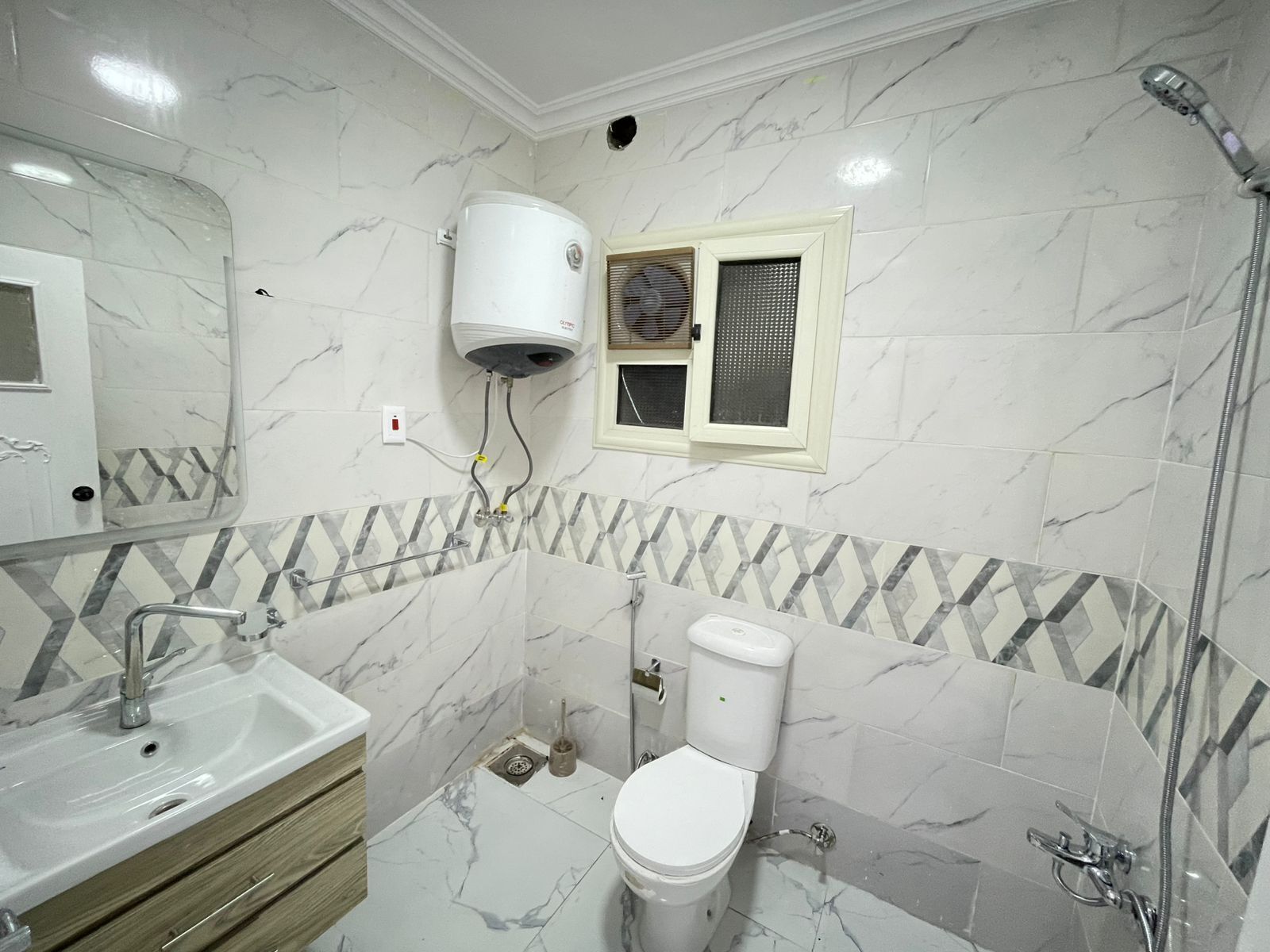 Une salle de bain avec un sol en marbre, un lavabo, des toilettes et une douche.