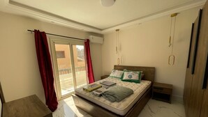 Et soveværelse med seng, natbord, et træskab, en skydedør af glas og en aircondition.