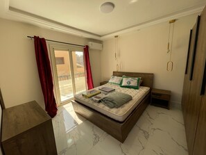 A bedroom with a bed, a nightstand, a wooden wardrobe, a sliding glass door, and an air conditioning unit. - 3B-Modern furniture apartment
3 cozy bedrooms with modern furniture (Cairo Governorate)