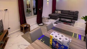 En moderne stue med en sofa, et spisebord med toiletpapir og en lysekrone.